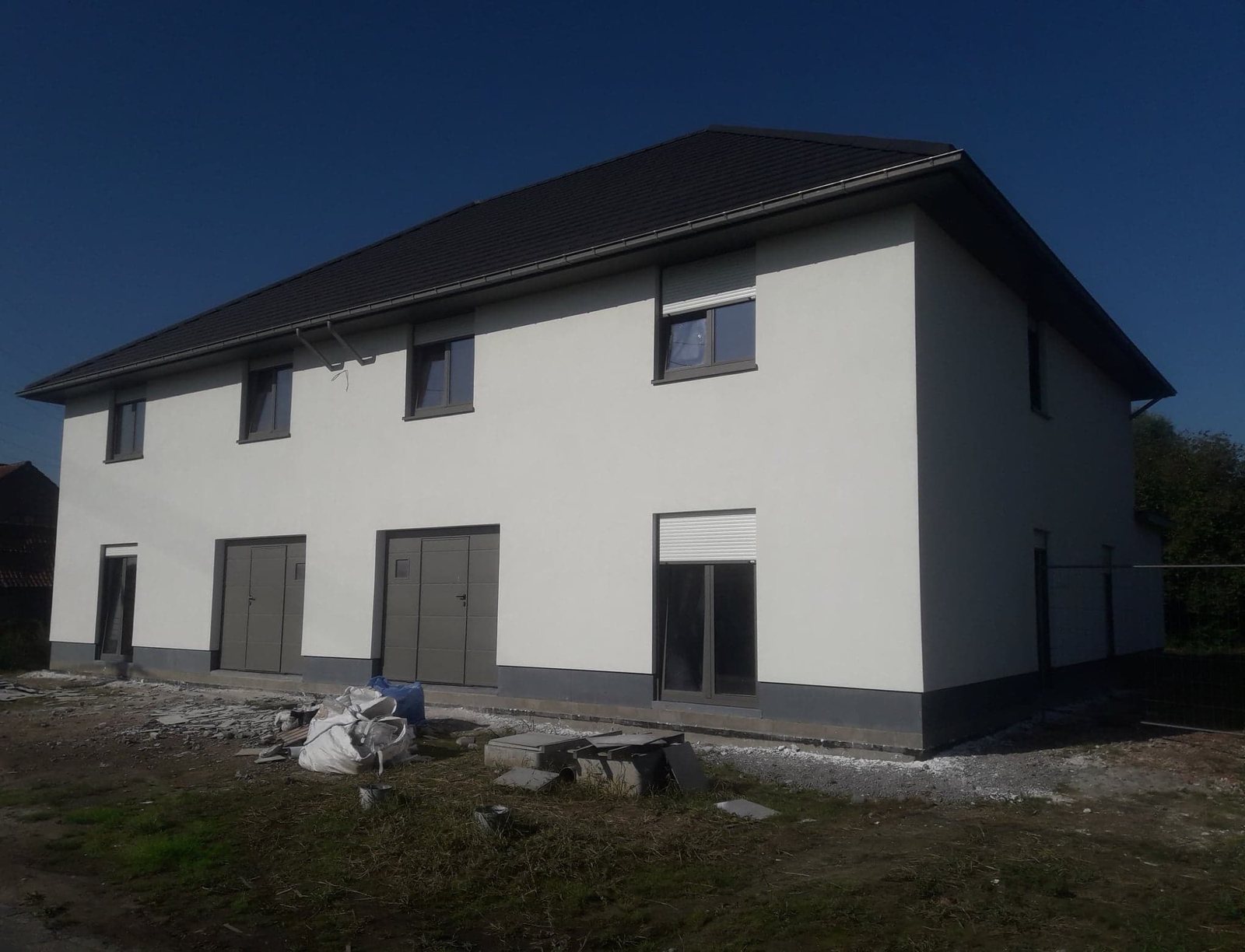 Wit gepleisterde woning met grijze plint en donker dak