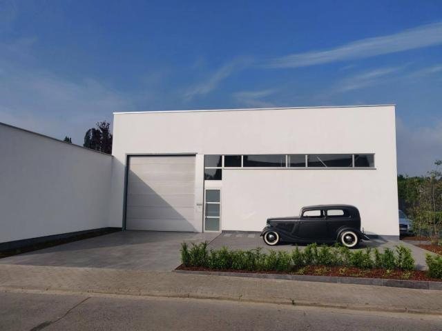 Wit gepleisterd gebouw met poort en oldtimer in Opstal